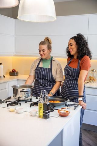 Diverse Women Cooking Together in Modern Kitchen with Smiles