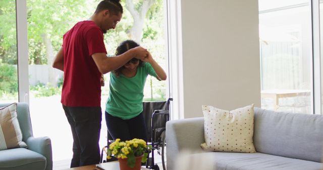 Person in supportive role helping their partner out of wheelchair signifies teamwork and kindness. Sunlit room enhances positive atmosphere. Ideal for themes of care, domestic lifestyle, health, and support. Suitable for blogs, healthcare articles, and lifestyle magazines emphasizing rehabilitation and living with physical disability.