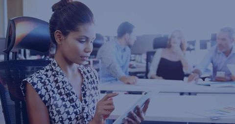 Focused professional woman using tablet in modern office collaborating with team