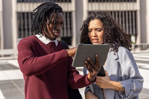 Young professionals collaborating on tablet on urban rooftop during outdoor work session