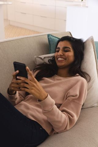 Young Woman Relaxing on Sofa with Smartphone in Modern Living Room