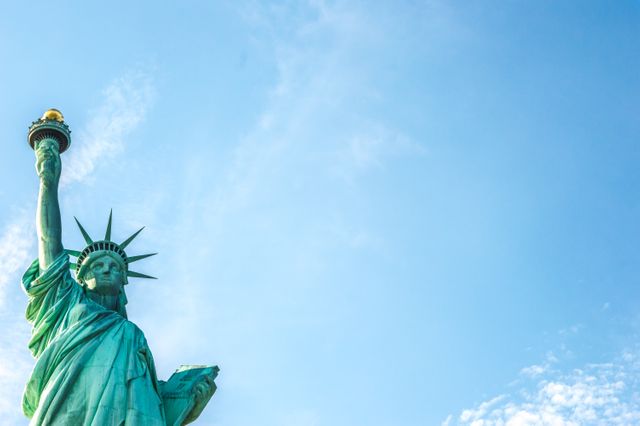 Depicting a close-up view of the Statue of Liberty with a clear blue sky serving as the backdrop. Suitable for illustrating concepts related to freedom, American history, national landmarks, tourism advertisements, travel brochures, and patriotic events. Ideal for use in projects aiming to highlight New York City attractions or iconic symbols of the United States.