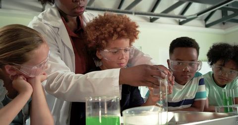 African-american teacher guiding diverse students conducting hands-on chemistry experiment