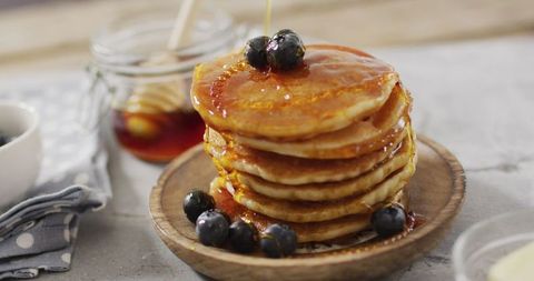 Stack of pancakes with blueberries and maple syrup topping