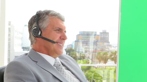 Senior Businessman Engaged in Phone Call with Headset