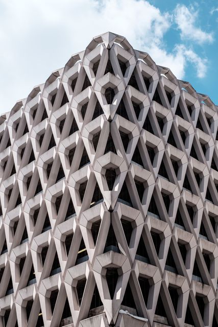 Close-up capture of a modern building showcasing a unique geometric pattern in its exterior design. The structure is made of concrete, and the style exhibits an architectural marvel. Ideal for use in articles or blogs about architecture, urban development, engineering, or modern design trends.
