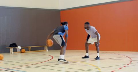 Young players dribbling and defending one-on-one during indoor basketball training session
