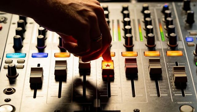Audio engineer adjusting mixing console fader with illuminated star button