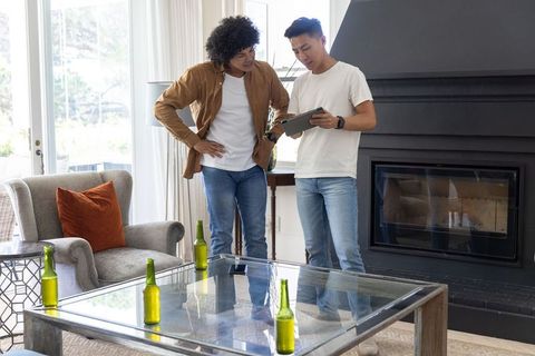 Friends reviewing tablet in modern living room with glass coffee table and green bottles