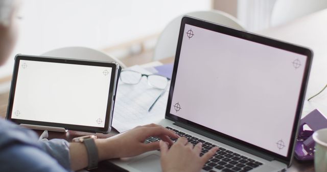 Person using laptop and tablet at desk, ideal for content about remote work, technology use in office environments, and productivity tools.