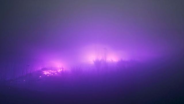 Ethereal Purple Glow Over Misty Field at Nighttime