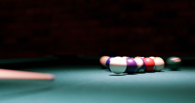 A close-up view of billiard balls arranged in a triangle on a pool table, with copy space. The focus on the colorful balls against the green felt sets the stage for an engaging game of pool.