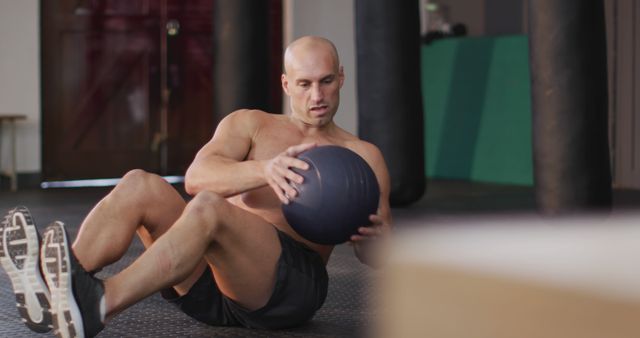 Fit caucasian man performing abs exercise with medicine ball at the gym. sports, training and fitness concept