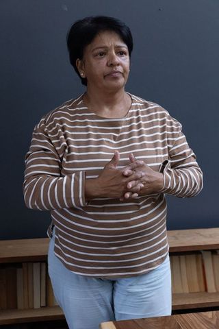 Senior Indian Woman Standing Thoughtfully by Dark Grey Wall