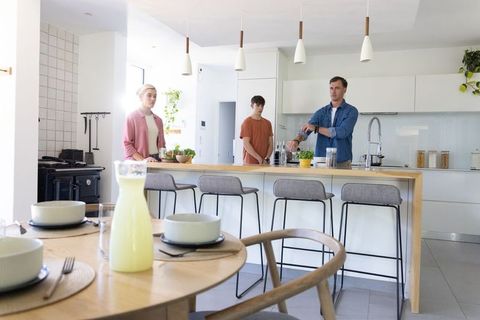 Modern family preparing breakfast in sunlit open-plan kitchen with wooden island