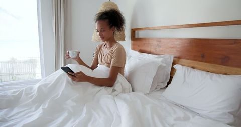 Woman Relaxing in Bed with Coffee and Tablet in Tranquil Bedroom