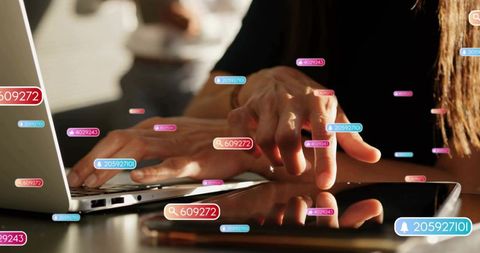 Hands typing on laptop and tapping tablet while digital notification badges float