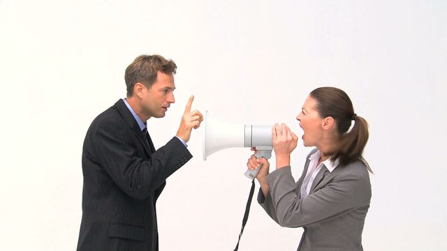 Businesswoman shouting through megaphone at colleague in white background suggesting workplace conflict or confrontation. Useful for concepts related to communication issues, work stress, or professional conflicts. Ideal for presentations, articles, and marketing content depicting office disagreements or demanding situations.