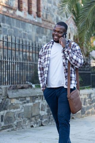 African American Man Walking and Talking on Phone with Crossbody Bag Urban Commuter Style