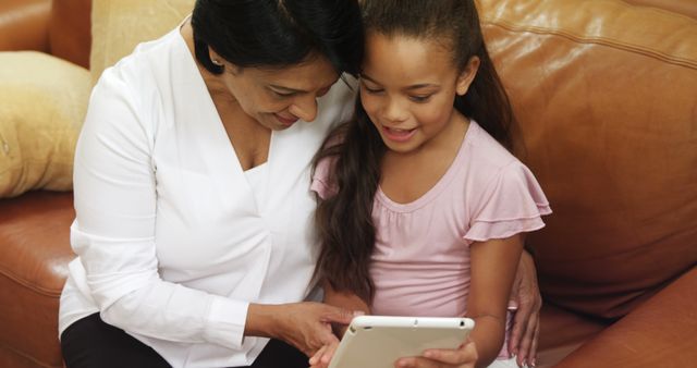 Grandmother and granddaughter bonding over tablet on cozy couch - Download Free Stock Images Pikwizard.com