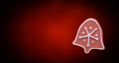 Festive gingerbread bell cookie on red background