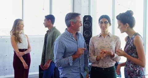 Colleagues Engaging in Workplace Discussion Near Large Windows