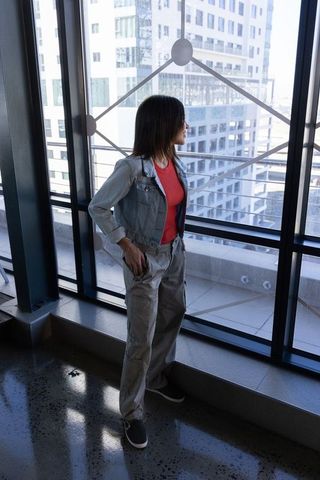 Asian woman standing by glass wall with geometric decal overlooking skyline