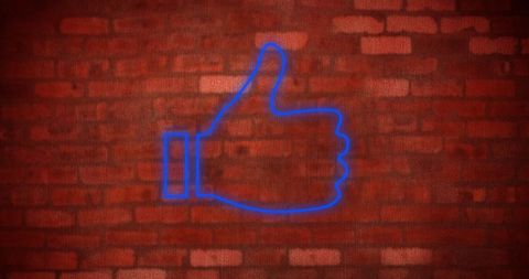 Neon thumbs up icon on brick wall background