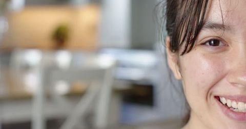 Asian woman smiling in cozy kitchen, half face and warm atmosphere