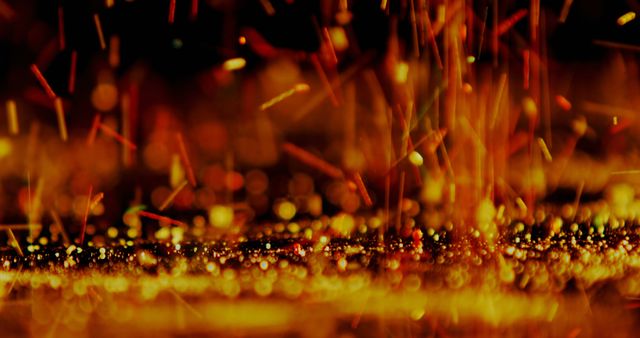 This abstract close-up imagery of glowing embers and sparks captures dynamic light trails in warm orange and yellow hues. It can be effectively used in creative design projects, backgrounds, presentations, or to symbolize energy, heat, and dynamic movement.
