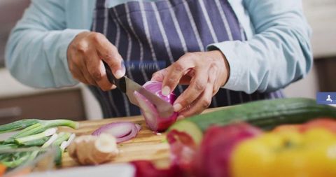 Home cook slicing red onion on cutting board in kitchen