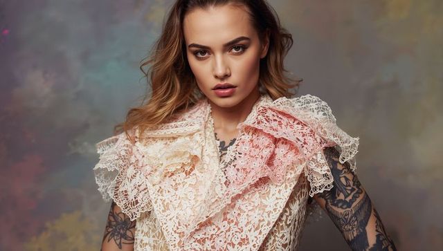 Model wearing layered lace ruffled collar showing tattooed arms and edgy high-fashion