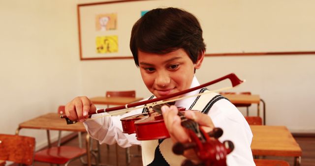 Young boy playing violin in classroom setting. Suitable for educational content, music programs, advertisements for music schools, or articles on childhood education and music.