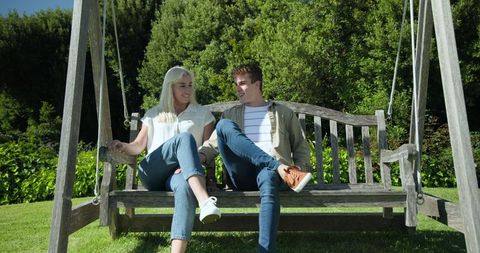 Happy Couple Enjoying Sunny Day on Wooden Garden Swing