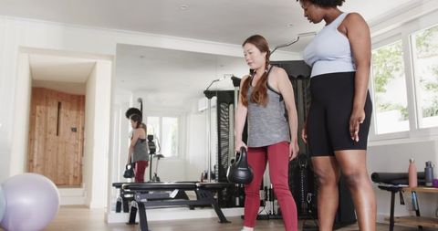 Fitness Training with Trainer Guiding Kettlebell Exercise in Home Gym