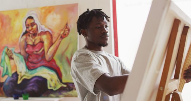 African american male painter painting on canvas in artist studio. art, creative and leisure time concept.