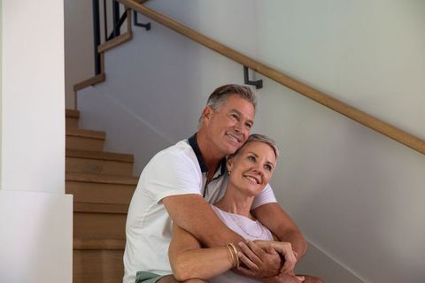Senior Couple Embracing on Wooden Staircase with Warm Smiles
