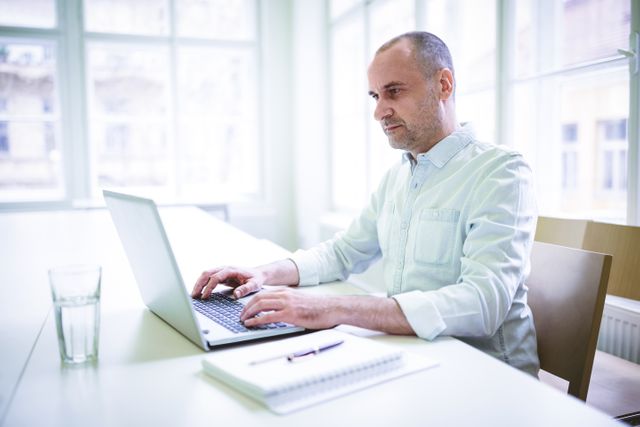 Confident businessman using laptop in creative office