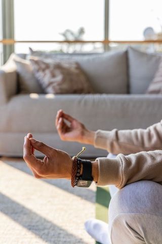 Sunlit meditation closeup showing mindful hand mudra with smartwatch on casual sofa