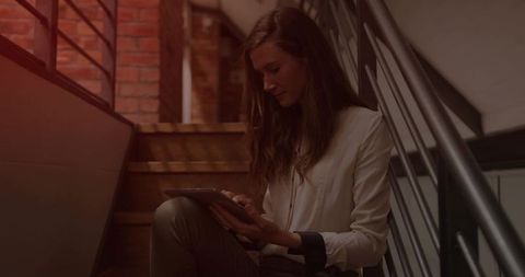 Woman Using Tablet on Loft Staircase in Creative Urban Workspace