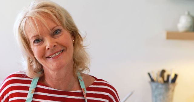 Happy Mature Woman in Kitchen Wearing Striped Shirt and Apron - Download Free Stock Images Pikwizard.com