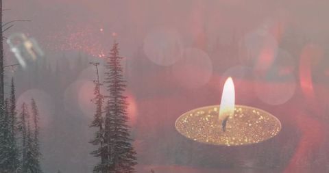 Glowing tealight candle flickering over misty evergreen forest with golden bokeh glow