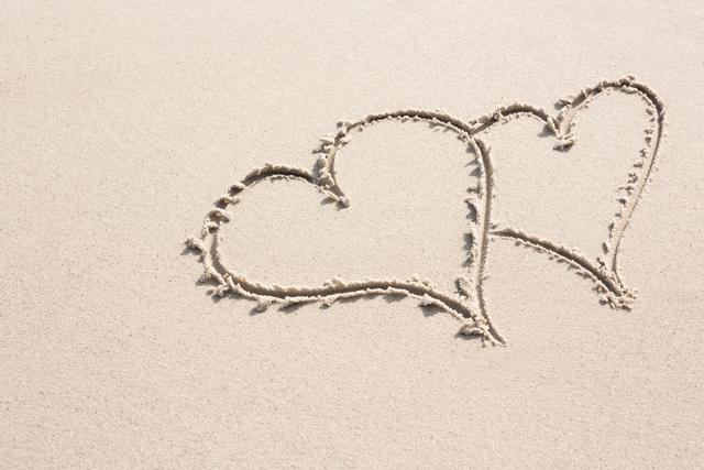 Two heart shapes drawn on sandy beach, symbolizing love and romance. Ideal for use in romantic, vacation, or summer-themed projects. Perfect for wedding invitations, travel brochures, or social media posts celebrating love and relationships.