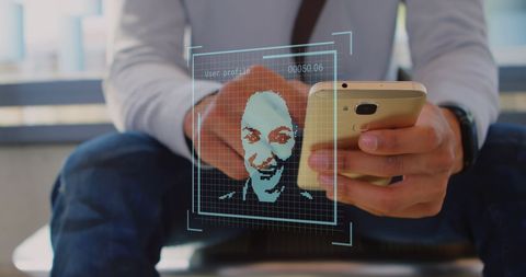 Businessman using smartphone with digital facial recognition icons overlay