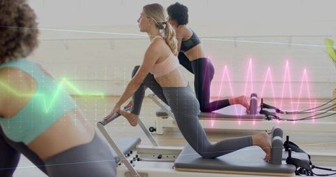 Group reformer pilates class practicing core strength with neon fitness data overlay