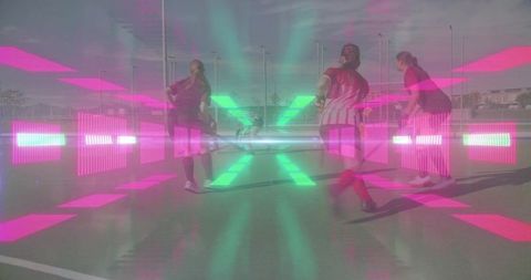 Female field hockey team clustering around ball on outdoor court with neon overlay