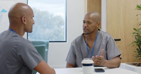 African american healthcare workers conversing in staff lounge during coffee break
