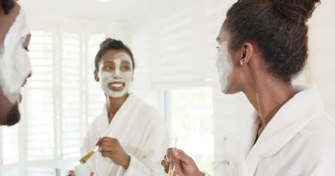 African-american couple applying facial masks together in bright bathroom morning routine