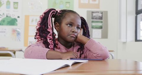 Bored child student daydreaming at desk in classroom