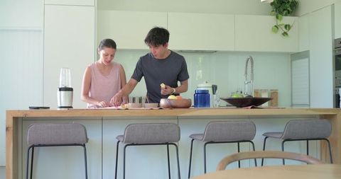 Diverse Couple Chopping Citrus on Wooden Kitchen Island, Modern Home Cooking Scene